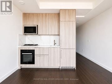 Toronto (Bayview Village) condo for rent - A kitchen with wooden cabinets and a black microwave.