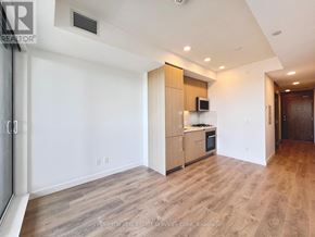 Toronto (Bayview Village) condo for rent - A spacious room with wooden flooring and a kitchenette in the corner.