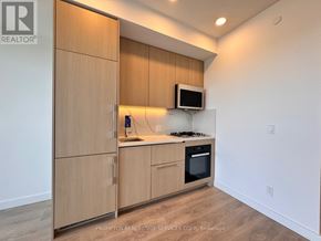 Toronto (Bayview Village) condo for rent - A kitchen area with wooden cabinets and a microwave on the counter.