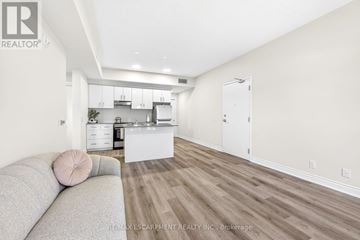 Hamilton (Stoney Creek) condo for rent - A living room with a grey couch and a kitchen in the background.
