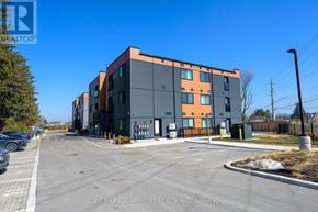 Hamilton (Stoney Creek) condo for rent - A modern multi-story building with a parking lot in front.