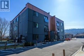Hamilton (Stoney Creek) condo for rent - A modern building with a red and black facade is the main focus of the image.