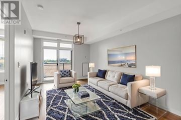 Burlington (Uptown) condo for rent - A well-lit living room with a glass coffee table and a large window.