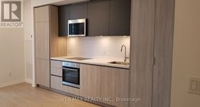 Toronto (Waterfront Communities) condo for rent - A modern kitchen with wooden cabinets and a stainless steel oven.