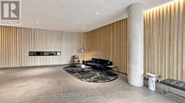 Toronto (Englemount-Lawrence) condo for rent - A modern living room with a black sofa and wooden wall paneling.