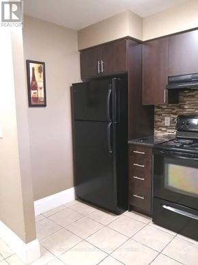 Toronto (New Toronto) condo for rent - A black refrigerator in a kitchen with brown cabinets and a stove.