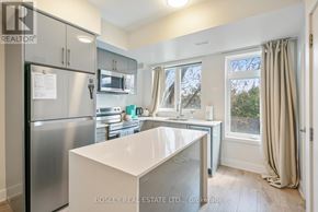 Niagara Falls (Arad/Fallsview) townhouse for rent - A kitchen with a refrigerator, microwave, and a window with curtains.