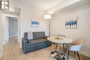 Niagara Falls (Arad/Fallsview) townhouse for rent - A living room with a grey couch, a round table with a white tablecloth and a chair.
