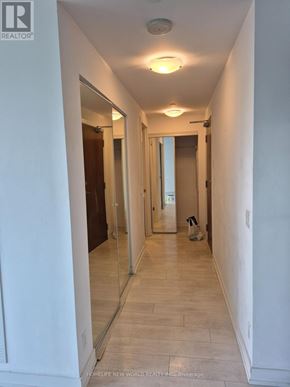 Toronto (Mimico) condo for rent - A long white hallway with a mirror on the wall.