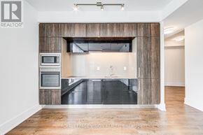 Toronto (Waterfront Communities) condo for rent - A modern kitchen with a wooden accent wall and stainless steel appliances.