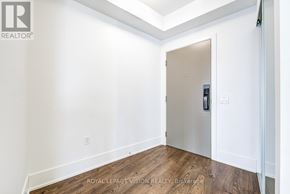 Toronto (Waterfront Communities) condo for rent - A white door with a handle and a keypad is in a room with white walls and wood flooring.