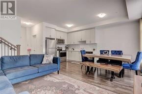 Vaughan (Vaughan Grove) townhouse for rent - A well-lit, modern living room with a blue sofa and a dining area with a table and chairs.