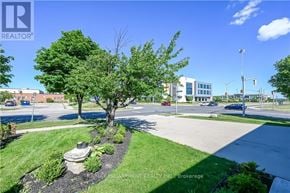 Hamilton (Stoney Creek) apartment for rent - A realtor photo of a landscaped area with a tree and a bench.