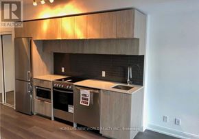 Toronto (Moss Park) condo for rent - A modern kitchen with stainless steel appliances and wooden cabinets.