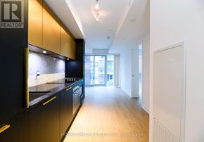 Toronto (Church-Yonge Corridor) condo for rent - A modern kitchen with dark cabinets and a wooden floor.