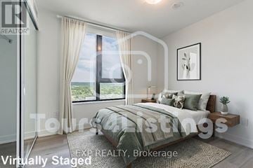 Burlington (Brant) condo for rent - A bedroom with a large bed and a window overlooking the city.