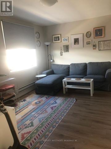 Toronto (Palmerston-Little Italy) fourplex for rent - A living room with a grey couch and a white coffee table.