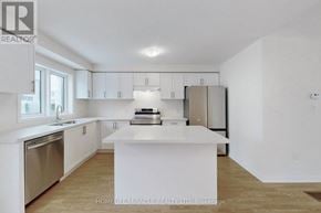 Oshawa (Eastdale) townhouse for rent - A white kitchen with a refrigerator, stove, and sink.