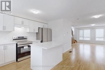 Oshawa (Eastdale) townhouse for rent - A spacious kitchen with white cabinets and a central island.