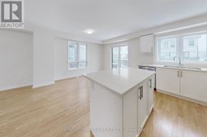 Oshawa (Eastdale) townhouse for rent - A well-lit, spacious kitchen with wooden flooring and white cabinetry.