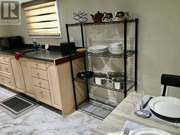 Niagara Falls (Stamford) apartment for rent - A kitchen with a black countertop and a wooden cabinet with a microwave and toaster on it.