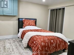 Niagara Falls (Stamford) apartment for rent - A bedroom with a bed covered in a red floral duvet.