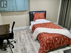 Niagara Falls (Stamford) apartment for rent - A bedroom with a bed covered in red bedding and a chair in front of a desk.