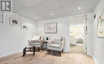 Oshawa (Mclaughlin) apartment for rent - A living room with a white couch, a black coffee table, and a painting on the wall.