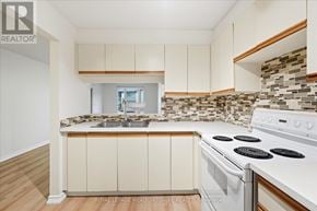 Toronto (Long Branch) condo for rent - A kitchen with a white stove top oven and white cabinets.