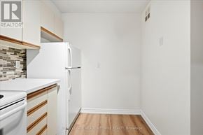 Toronto (Long Branch) condo for rent - A white refrigerator in a kitchen with white walls and wood flooring.