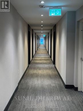 Oakville (Go Glenorchy) condo for rent - A long hallway with a green exit sign at the end.