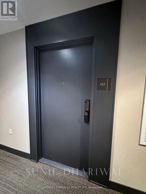 Oakville (Go Glenorchy) condo for rent - A black door with a handle and a number 122 on the wall.