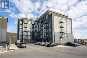 Hamilton (Waterdown) condo for rent - A building with a parking lot in front of it.
