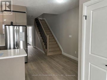 Welland (Lincoln/Crowland) townhouse for rent - A kitchen with a refrigerator and a staircase in the background.