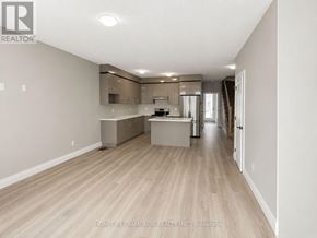 Welland (Lincoln/Crowland) townhouse for rent - A spacious, empty room with wooden flooring and a kitchen area in the background.