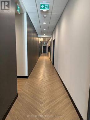 Kitchener condo for rent - A long hallway with a green exit sign on the ceiling.