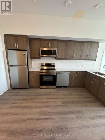 Kitchener condo for rent - A kitchen with wooden cabinets and a white fridge.