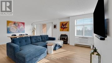 Guelph (Kortright West) condo for rent - A living room with a blue couch and a television mounted on the wall.