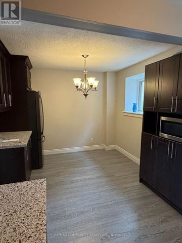 Toronto (West Hill) townhouse for rent - A kitchen with dark wood cabinets and a granite countertop.