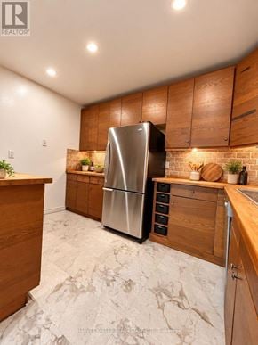 Toronto (Scarborough Village) townhouse for rent - A kitchen with a refrigerator, wooden cabinets, and a marble floor.