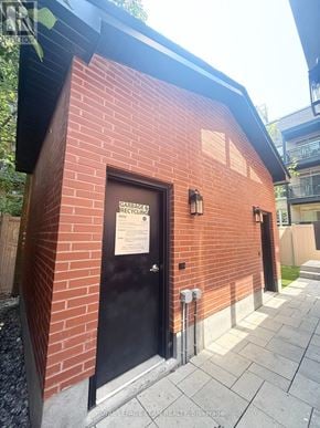 Ottawa apartment for rent - A small red brick building with a black door and a sign on it.