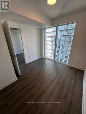 Toronto (Church-Yonge Corridor) condo for rent - A room with wooden flooring and a large window with a view of a building outside.