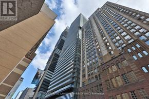 Toronto (Bay Street Corridor) condo for rent - A tall building with a glass facade stands between two shorter buildings.
