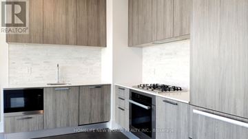 Toronto (Church-Yonge Corridor) condo for rent - A modern kitchen with wooden cabinets and a white brick backsplash.