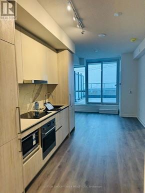 Vaughan (Vaughan Corporate Centre) condo for rent - A modern kitchen with wooden cabinets and a black countertop.