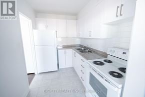 Toronto (Playter Estates-Danforth) condo for rent - A white kitchen with a stove and sink.