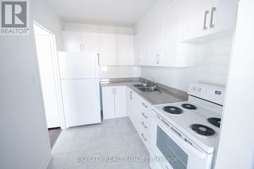 Toronto (Playter Estates-Danforth) condo for rent - A white kitchen with a stove and sink.