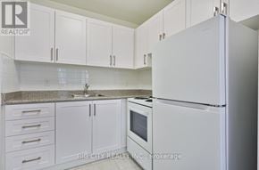 Toronto (Playter Estates-Danforth) condo for rent - A white refrigerator in a kitchen with white cabinets.