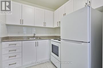 Toronto (Playter Estates-Danforth) condo for rent - A white refrigerator in a kitchen with white cabinets.