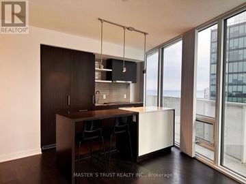 Toronto (Waterfront Communities) condo for rent - A modern kitchen with dark wood cabinets and a white countertop.
